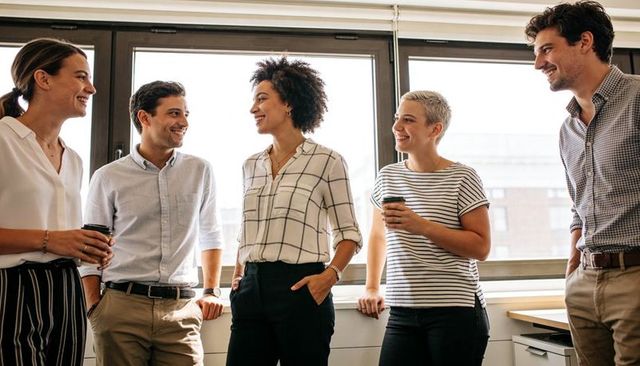 Colleagues Chatting by Window During Coffee Break in Bright Modern Office