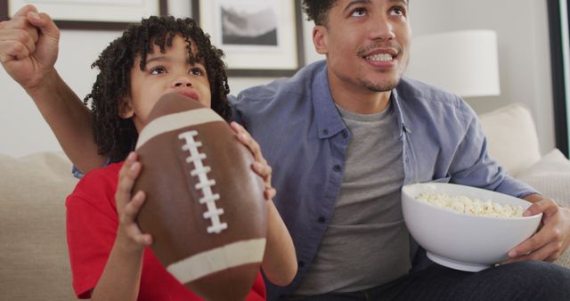 Father and Son Watching Football Game Holding Football and Popcorn - Download Free Stock Images Pikwizard.com