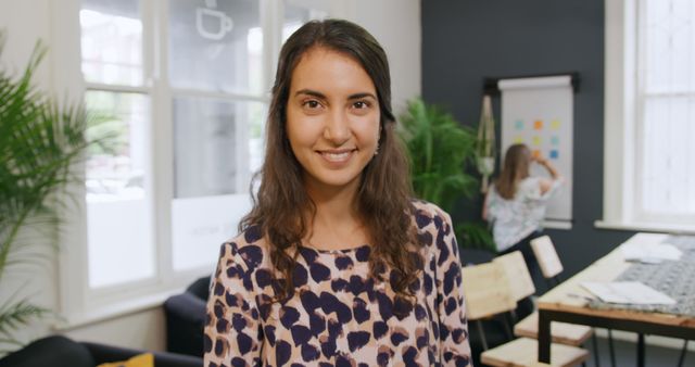 Confident Woman Smiling in Modern Office with Colleague in Background - Download Free Stock Images Pikwizard.com