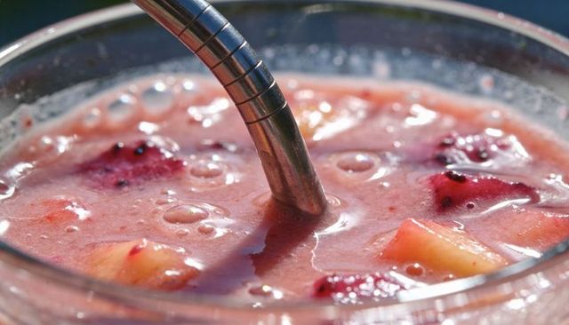Refreshing pink fruit smoothie with metal straw closeup showing bubbles and fruit chunks