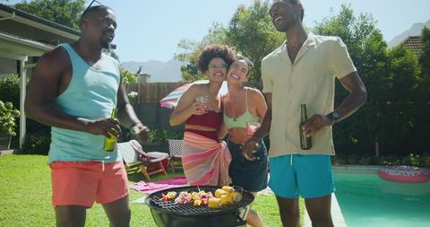 Diverse Friends Grilling by Backyard Pool Holding Drinks on Sunny Day