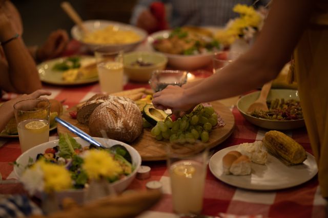 Mid section of multi-generation Caucasian family gathered around a table, eating a meal at home, standing and serving food and enjoying time together