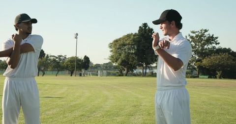 Diverse cricket teammates stretching and warming up on sunny outfield before match