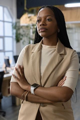 Confident african american businesswoman standing arms crossed in modern open-plan office