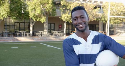 Confident Rugby Player Holding Ball on Outdoor Sports Field