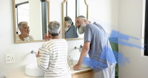 Mature couple at double vanity touching face and leaning with blue digital data overlay
