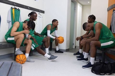 Multicultural basketball teammates resting and laughing in locker room after game