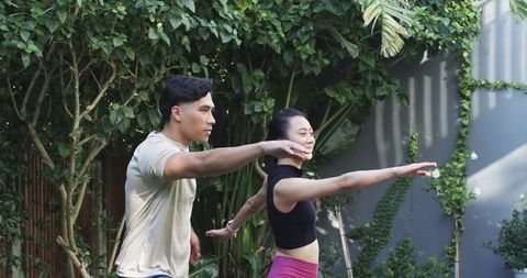 Young couple practicing balance stretches together in lush backyard fitness routine session