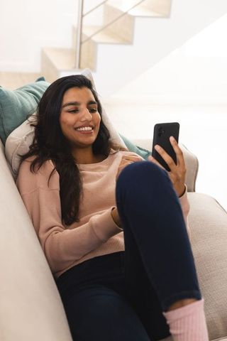 Relaxed Woman Using Smartphone at Home DisclaimerIfirting in it