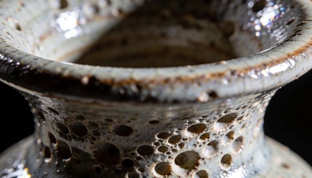 Glazed ceramic vase rim with bubbled speckled glaze and pitted glossy texture