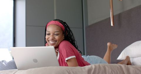 Happy Woman Relaxing on Bed with Laptop