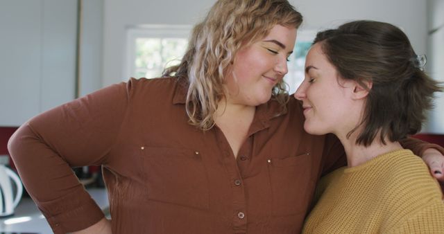 Happy caucasian lesbian couple embracing and looking at each other at home. domestic life and leisure time.
