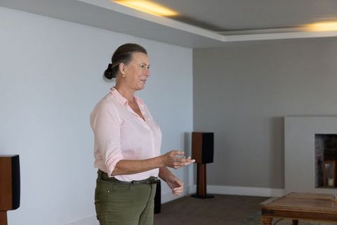 Senior woman relaxing in modern living room with fireplace
