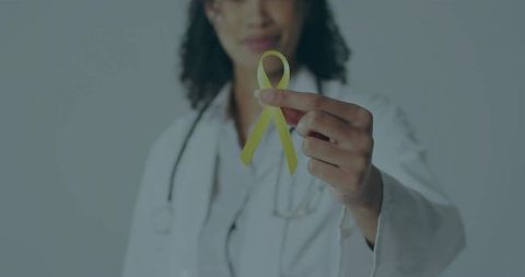 Female doctor holding yellow awareness ribbon for health advocacy