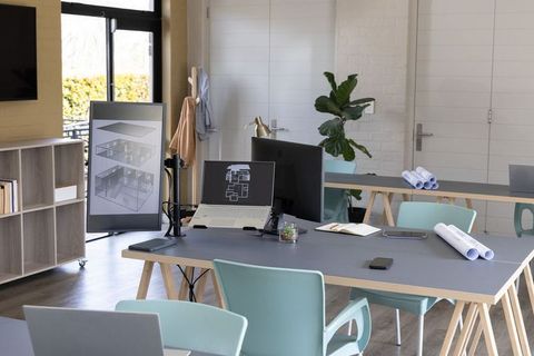 Architectural studio workspace showing laptop with floorplans and vertical monitor display