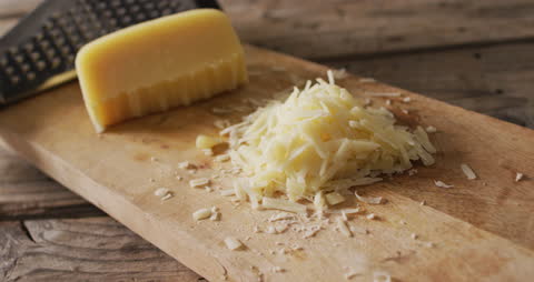 Grated Cheese and Block on Wooden Board