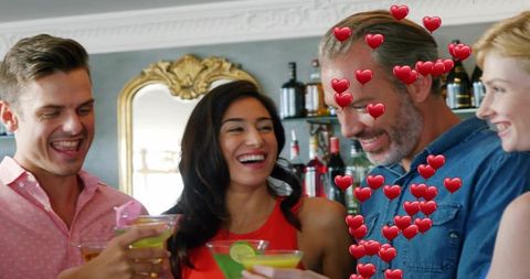 Friends laughing and toasting with colorful martinis at stylish bar with heart emojis