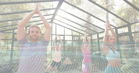 Man Leading Group Yoga Class in Glass Greenhouse, Balancing Tree Pose in Natural Light