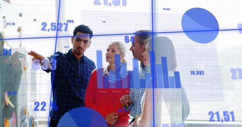 Business Team Analyzing Data Visualization on Glass Wall Pointing at Charts and Graphs