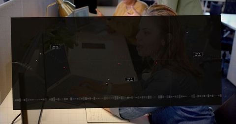 Typing woman using laptop at open office with transparent analytics dashboard overlay