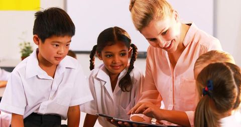 Teacher Engaging Students with Tablet in Bright Classroom