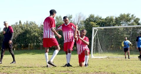 Team Scoring Celebration on Field with Referee in Background