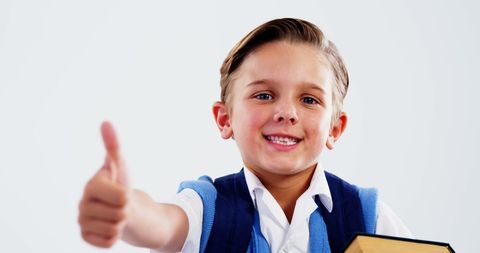 Cheerful Boy Holding Book Giving Thumbs Up Celebrating Success