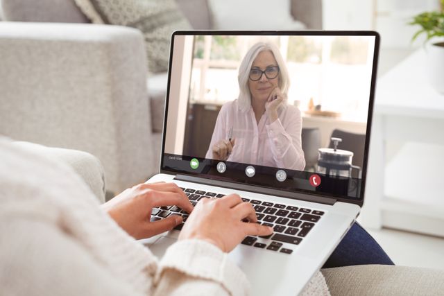 Caucasian mature businesswoman during video call with caucasian female colleague on laptop at home. unaltered, work from home, business, wireless technology, working, teamwork and office concept.