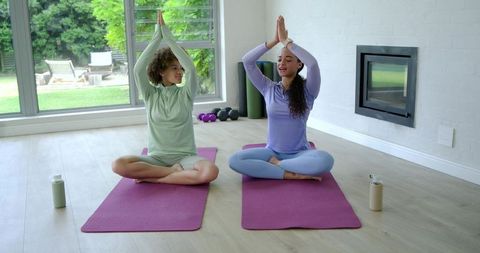 African american women practicing seated yoga on purple mats at home for mindfulness and balance