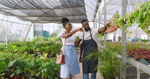 Customer engaged with plants in greenhouse with nursery staff