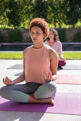 Women meditating outdoors by pool for wellness and serenity