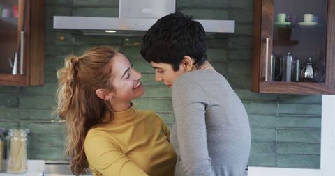 Candid Lesbian Couple Embracing, Finding Joy in Home Kitchen Setting
