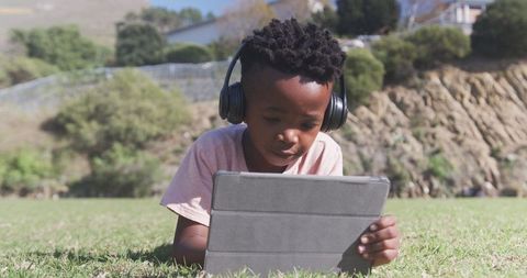 Young Boy Studying Outdoors with Tablet and Headphones