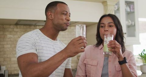 Happy Couple Enjoying Fresh Smoothie in Kitchen Together