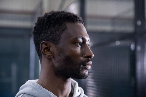 Focused african american athlete facing right in industrial gym wearing gray hoodie