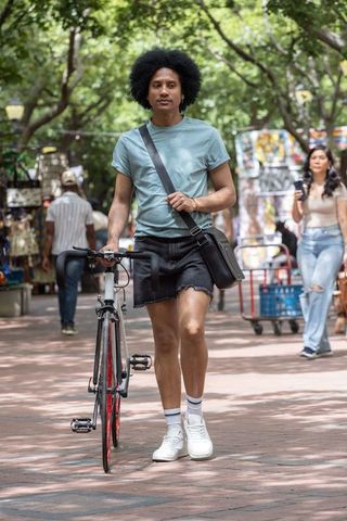 African american man walking bicycle through urban market on sunlit brick path