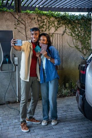 Happy Couple Taking Selfie at Carport with Travel Documents