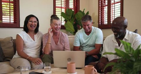Diverse Middle-aged Friends Relaxing with Laptop in Cozy Living Room Setting