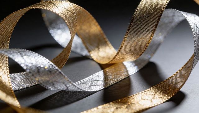 Glittering gold and silver ribbons looping on dark surface for festive luxury background