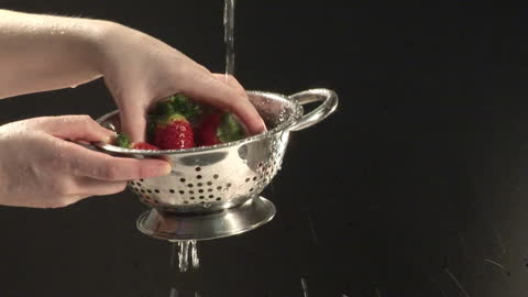 Washing Fresh Strawberries with Running Water in Metal Colander