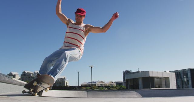 Caucasian man riding and jumping on skateboard on sunny day. hanging out at skatepark in summer.