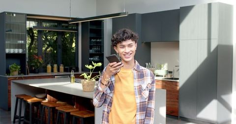 Young Male Using Smartphone in Modern Minimalist Kitchen