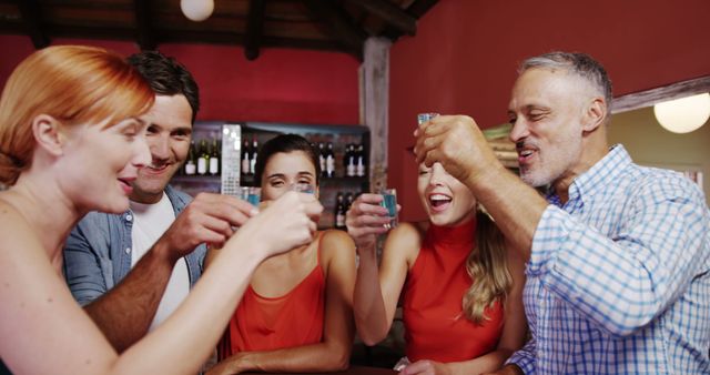 Group of friends toasting tequila in bar