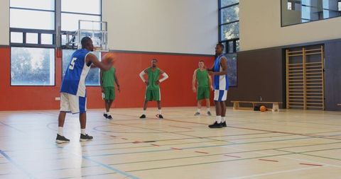 Basketball teammates executing driving layup and defensive rebound drill in gymnasium