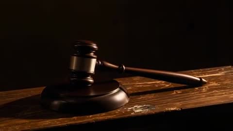 Camera zooming to judge gavel resting on worn wooden bench with dramatic low-key lighting