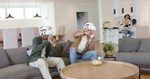 Two Friends Experiencing Virtual Reality Gaming on Couch in Modern Open-Plan Living Room