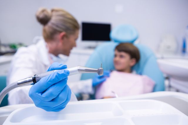 Close up of dentist holding medical equipment while examining boy at medical clinic