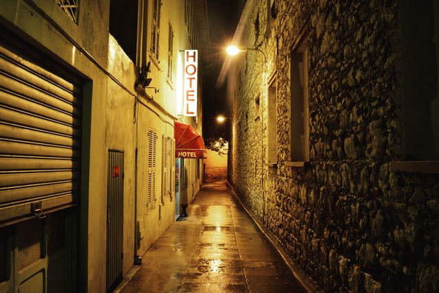 Narrow alley at night with illuminated hotel sign - Download Free Stock Photos Pikwizard.com