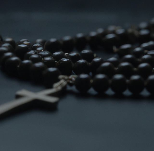 Close up of black rosary with cross on black background. Religion, faith and prayer concept.