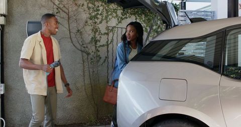 African American Couple Charging Electric SUV in Carport